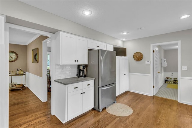 4212 NW Briarcliff Ln, Kansas City, MO 64116 - kitchen with freestanding refrigerator, light wood-type flooring, white cabinets, wainscoting, and backsplash