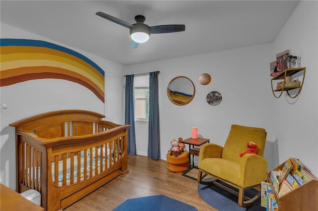 4212 NW Briarcliff Ln, Kansas City, MO 64116 - bedroom with wood finished floors, a crib, and a ceiling fan