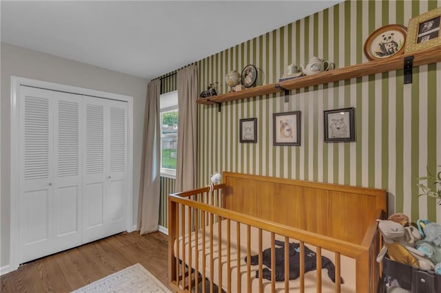 4212 NW Briarcliff Ln, Kansas City, MO 64116 - bedroom with wood finished floors, a closet, wallpapered walls, baseboards, and a nursery area