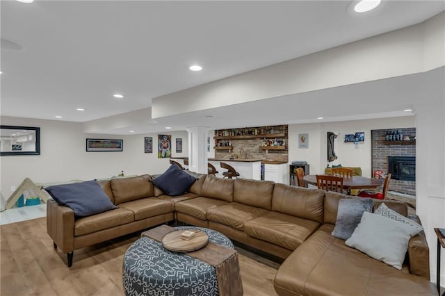 4212 NW Briarcliff Ln, Kansas City, MO 64116 - living room featuring bar, light wood-style flooring, recessed lighting, a brick fireplace, and decorative columns