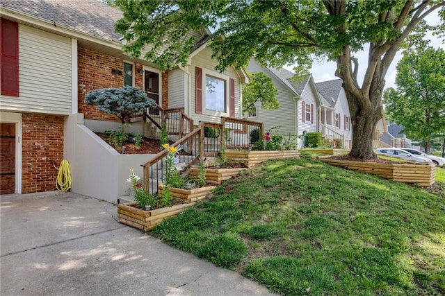 1209 NW Roanoke Dr, Blue Springs, MO 64015 - view of front of house with brick siding, roof with shingles, a front yard, and a vegetable garden
