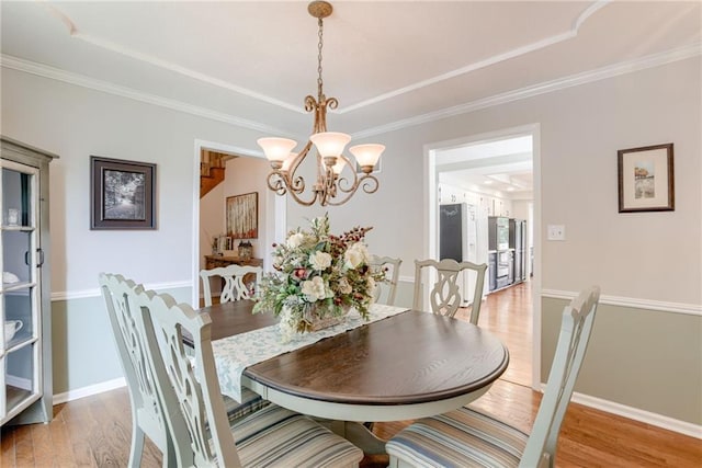 1209 NW Roanoke Dr, Blue Springs, MO 64015 - dining area featuring a chandelier, light wood-type flooring, a tray ceiling, and ornamental molding