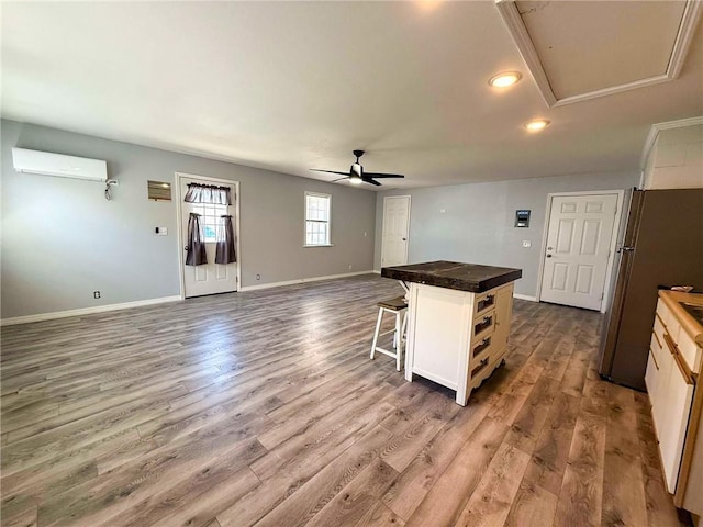 900 E 7th St, Galena, KS 66739 - kitchen featuring freestanding refrigerator, a wall unit AC, ceiling fan, a kitchen bar, and open floor plan