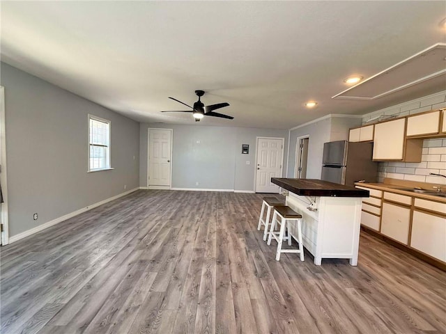 900 E 7th St, Galena, KS 66739 - kitchen with freestanding refrigerator, a sink, wood finished floors, a kitchen bar, and baseboards