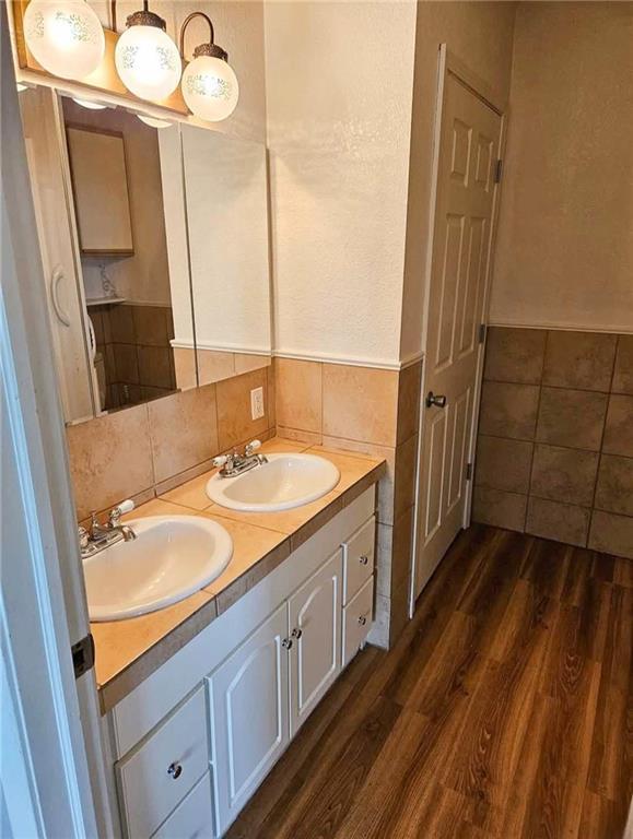 900 E 7th St, Galena, KS 66739 - full bathroom featuring wood finished floors, double vanity, and decorative backsplash