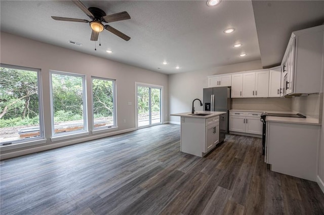 kitchen featuring a sink, dark wood finished floors, an island with sink, ceiling fan, and light countertops