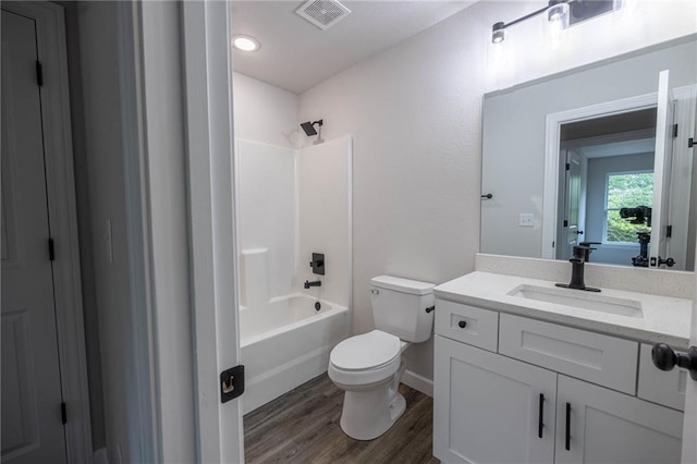 full bath with toilet, wood finished floors, vanity, bathing tub / shower combination, and baseboards