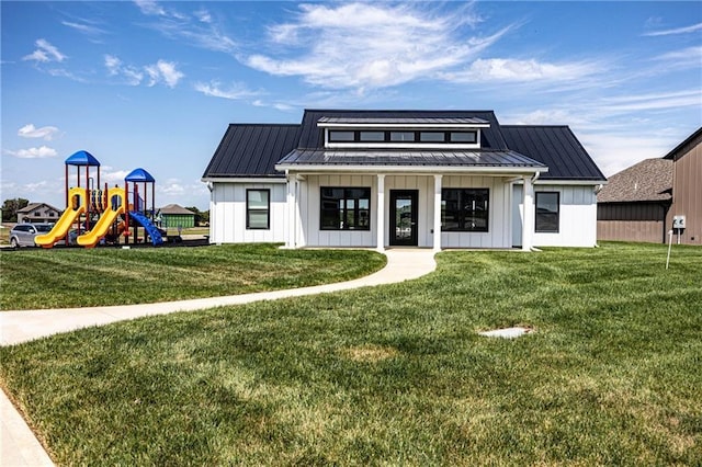view of front of house featuring board and batten siding, a standing seam roof, a front lawn, metal roof, and a playground