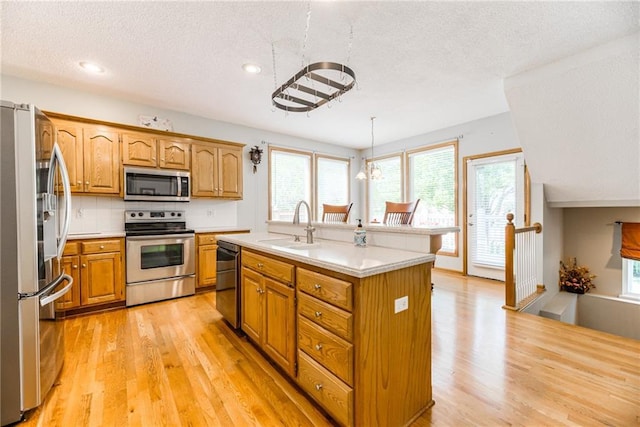 13238 Reeder St, Overland Park, KS 66213 - kitchen featuring appliances with stainless steel finishes, light wood finished floors, light countertops, plenty of natural light, and a textured ceiling