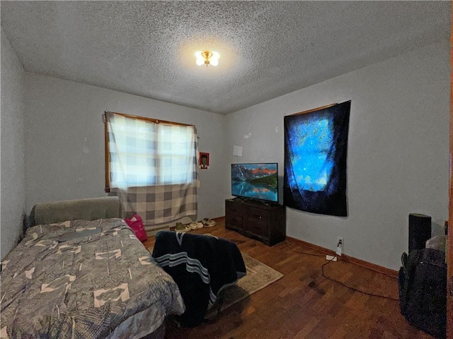 bedroom featuring wood finished floors, a textured ceiling, and baseboards