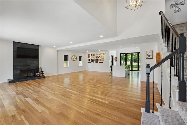 5263 SW Raintree Pkwy, Lees Summit, MO 64082 - unfurnished living room with light wood-style flooring, stairs, recessed lighting, a fireplace, and baseboards