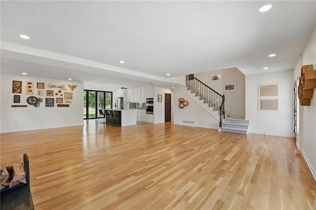 5263 SW Raintree Pkwy, Lees Summit, MO 64082 - unfurnished living room featuring recessed lighting, stairs, light wood-style floors, baseboards, and a textured ceiling