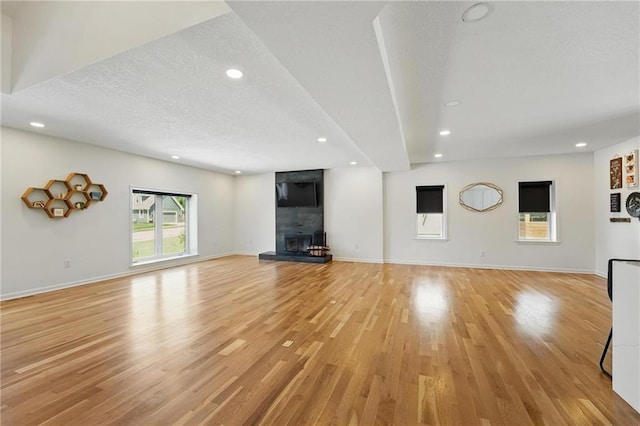 5263 SW Raintree Pkwy, Lees Summit, MO 64082 - unfurnished living room with a fireplace, recessed lighting, light wood-type flooring, baseboards, and a textured ceiling