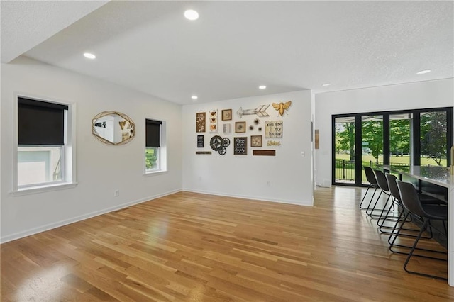 5263 SW Raintree Pkwy, Lees Summit, MO 64082 - unfurnished living room with healthy amount of natural light, light wood-type flooring, recessed lighting, baseboards, and a textured ceiling