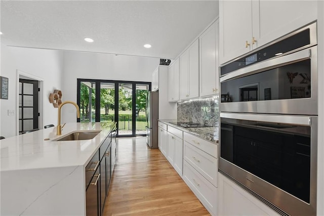 5263 SW Raintree Pkwy, Lees Summit, MO 64082 - kitchen featuring a sink, appliances with stainless steel finishes, white cabinetry, light wood finished floors, and a center island with sink
