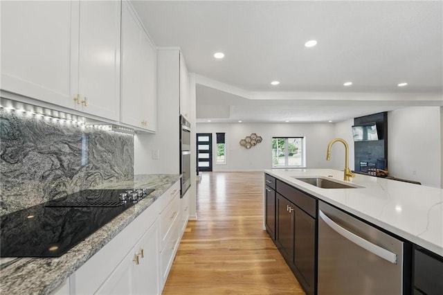 5263 SW Raintree Pkwy, Lees Summit, MO 64082 - kitchen with stainless steel dishwasher, a sink, light wood finished floors, black electric cooktop, and open floor plan