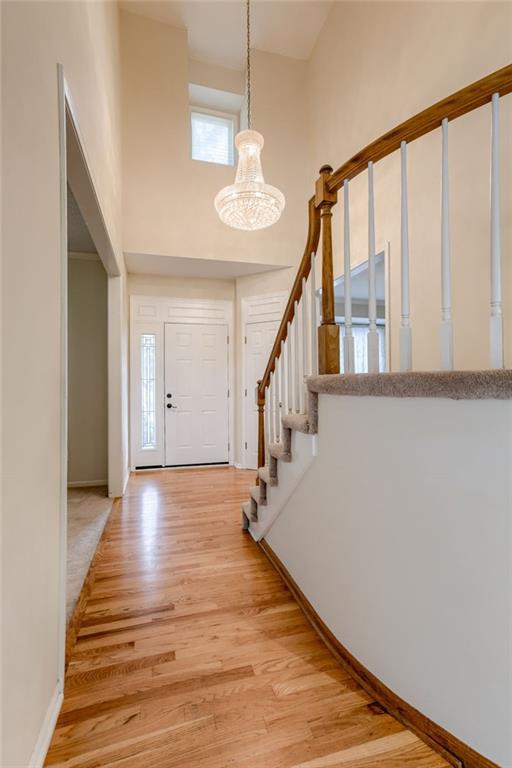 16482 W 132nd Cir, Olathe, KS 66062 - entryway with a chandelier, a high ceiling, light wood-style floors, stairway, and baseboards