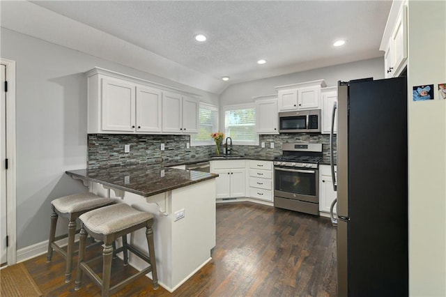 2511 E Maple Ct, Tonganoxie, KS 66086 - kitchen featuring appliances with stainless steel finishes, a peninsula, a sink, white cabinetry, and backsplash