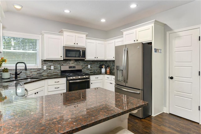 2511 E Maple Ct, Tonganoxie, KS 66086 - kitchen featuring appliances with stainless steel finishes, a sink, dark wood-style floors, decorative backsplash, and white cabinetry