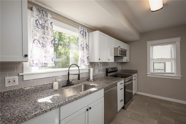 4219 Kenwood Ave, Kansas City, MO 64110 - kitchen featuring stainless steel appliances, white cabinets, decorative backsplash, and light stone counters
