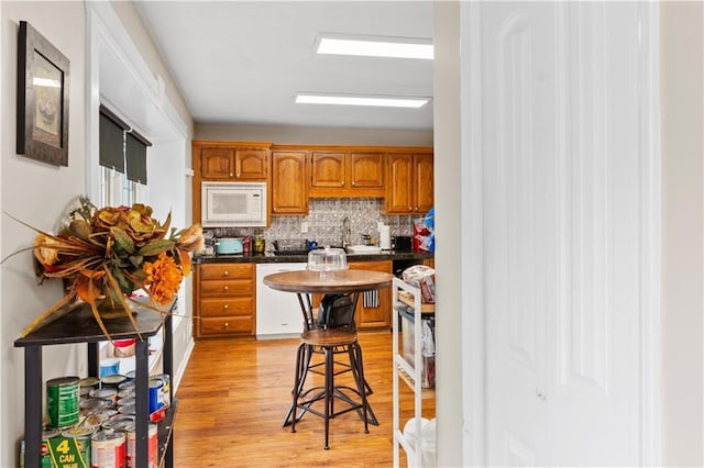 15205 E 40th St S, Independence, MO 64055 - kitchen featuring white appliances, dark countertops, backsplash, brown cabinets, and light wood-style floors