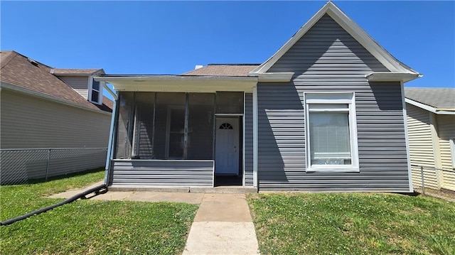 view of front of home with a sunroom and a front lawn