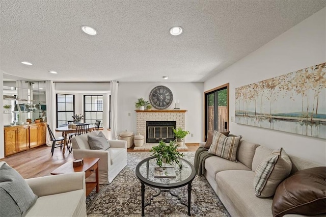 12332 W 105th Ter, Overland Park, KS 66215 - living room with a textured ceiling, wood finished floors, a brick fireplace, and recessed lighting