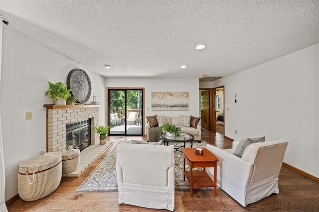 12332 W 105th Ter, Overland Park, KS 66215 - living room featuring a textured ceiling, a brick fireplace, recessed lighting, wood finished floors, and baseboards