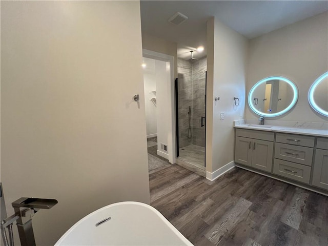 2320 NE 72nd St, Kansas City, MO 64118 - bathroom with a stall shower, vanity, wood finished floors, a freestanding bath, and baseboards