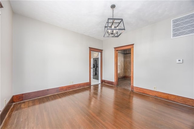 915 Main St, Neodesha, KS 66757 - unfurnished room with a chandelier, wood finished floors, and baseboards