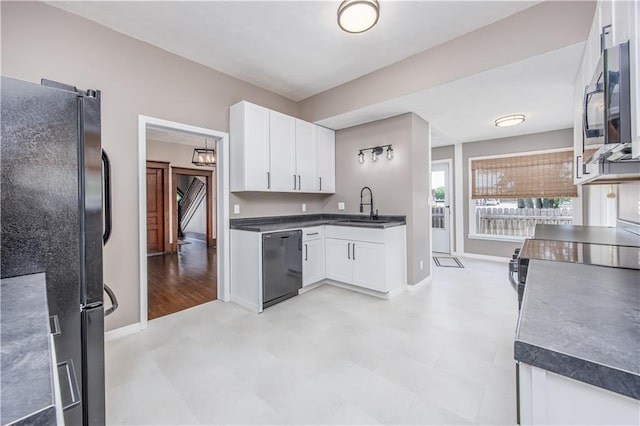 915 Main St, Neodesha, KS 66757 - kitchen with black appliances, a sink, dark countertops, and white cabinetry