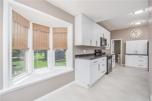 915 Main St, Neodesha, KS 66757 - kitchen with black appliances, white cabinetry, baseboards, and dark countertops