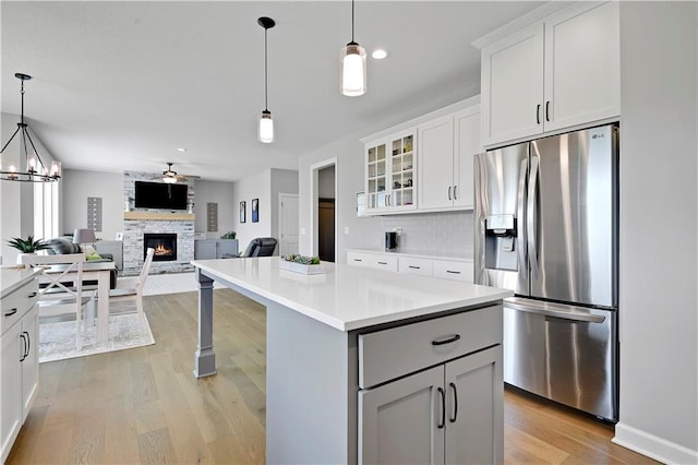 19629 W 196th St, Spring Hill, KS 66083 - kitchen featuring stainless steel fridge with ice dispenser, a stone fireplace, light wood finished floors, light countertops, and recessed lighting
