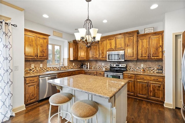 24318 W 91st Pl, Lenexa, KS 66227 - kitchen featuring stainless steel appliances, a sink, brown cabinets, a center island, and a chandelier