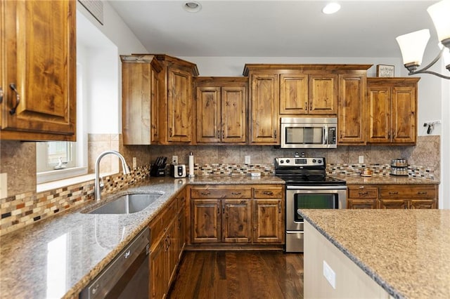 24318 W 91st Pl, Lenexa, KS 66227 - kitchen featuring stainless steel appliances, a sink, dark wood-style floors, light stone counters, and brown cabinets