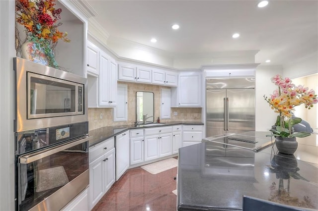 3109 W 118th St, Leawood, KS 66211 - kitchen featuring built in appliances, white cabinets, backsplash, recessed lighting, and granite tiled floors