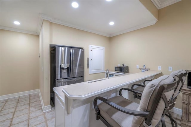 3109 W 118th St, Leawood, KS 66211 - kitchen featuring appliances with stainless steel finishes, a kitchen bar, a peninsula, ornamental molding, and light countertops