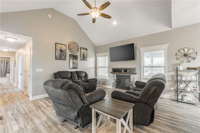 2808 E Cedar Pl, Tonganoxie, KS 66086 - living room featuring high vaulted ceiling, ceiling fan, baseboards, light wood-style floors, and a stone fireplace