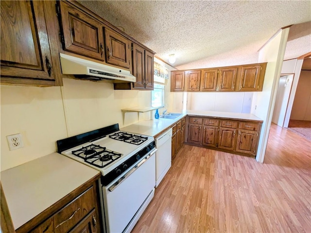 kitchen featuring white appliances, under cabinet range hood, a textured ceiling, light wood-style floors, and a sink