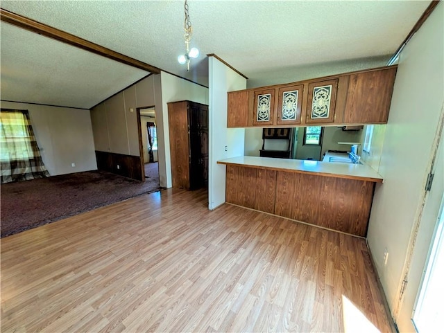 kitchen with light wood finished floors, brown cabinets, fridge, a textured ceiling, and vaulted ceiling
