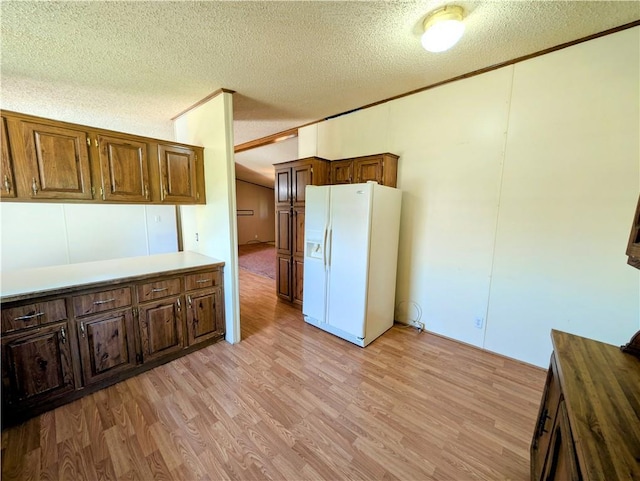 kitchen featuring white refrigerator with ice dispenser, a textured ceiling, light wood-style flooring, and light countertops