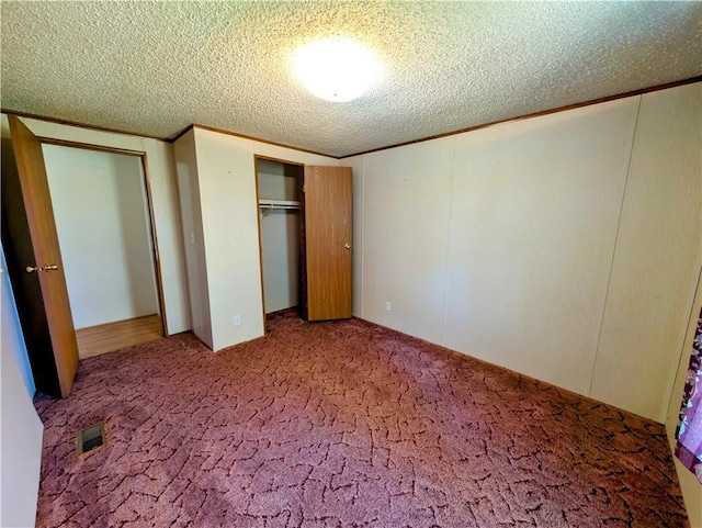 unfurnished bedroom featuring a textured ceiling, carpet, and a closet