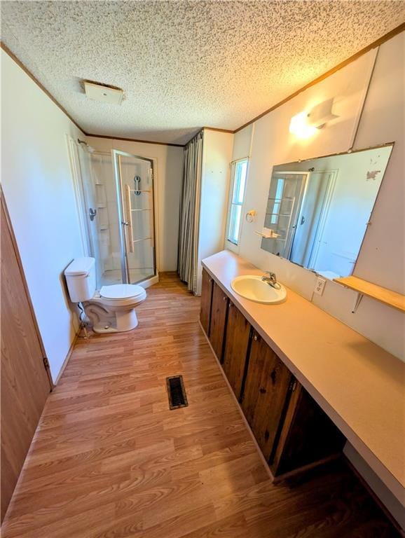 full bathroom with a stall shower, toilet, wood finished floors, a textured ceiling, and vanity