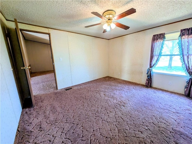 carpeted spare room with a ceiling fan and a textured ceiling