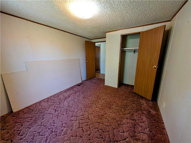 unfurnished bedroom with carpet floors, a closet, a textured ceiling, and ornamental molding