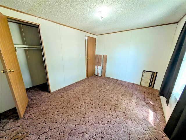 unfurnished bedroom featuring carpet flooring, a closet, a textured ceiling, ornamental molding, and a decorative wall
