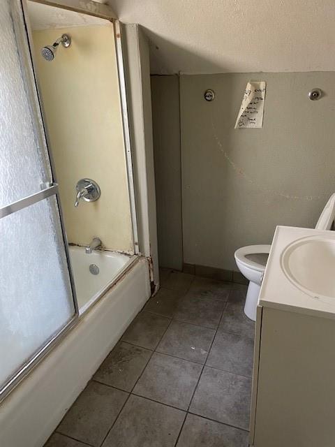 bathroom with enclosed tub / shower combo, vanity, tile patterned floors, toilet, and a textured ceiling