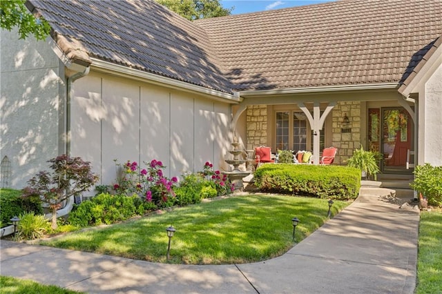 3644 W 127th Ter, Leawood, KS 66209 - property entrance featuring a tile roof, a porch, a yard, and stone siding