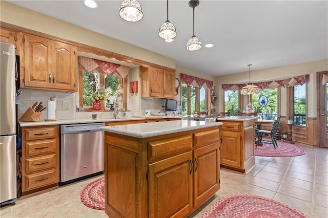 3644 W 127th Ter, Leawood, KS 66209 - kitchen featuring appliances with stainless steel finishes, a center island, light countertops, tasteful backsplash, and decorative light fixtures