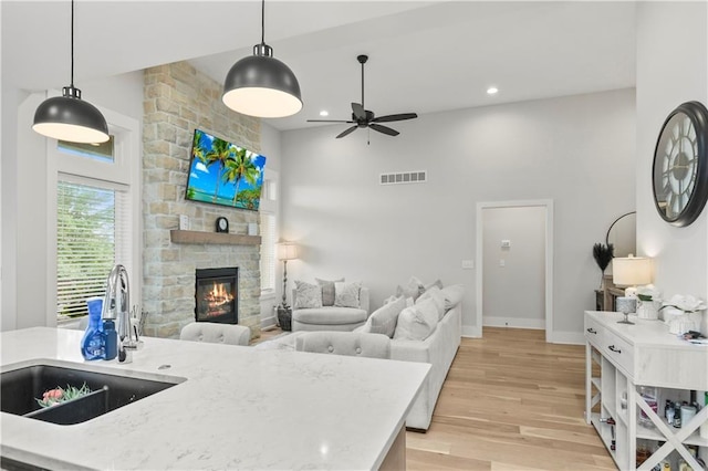 807 NE Algonquin St Unit B, Lees Summit, MO 64064 - kitchen with a sink, a ceiling fan, light wood-style flooring, a stone fireplace, and open floor plan